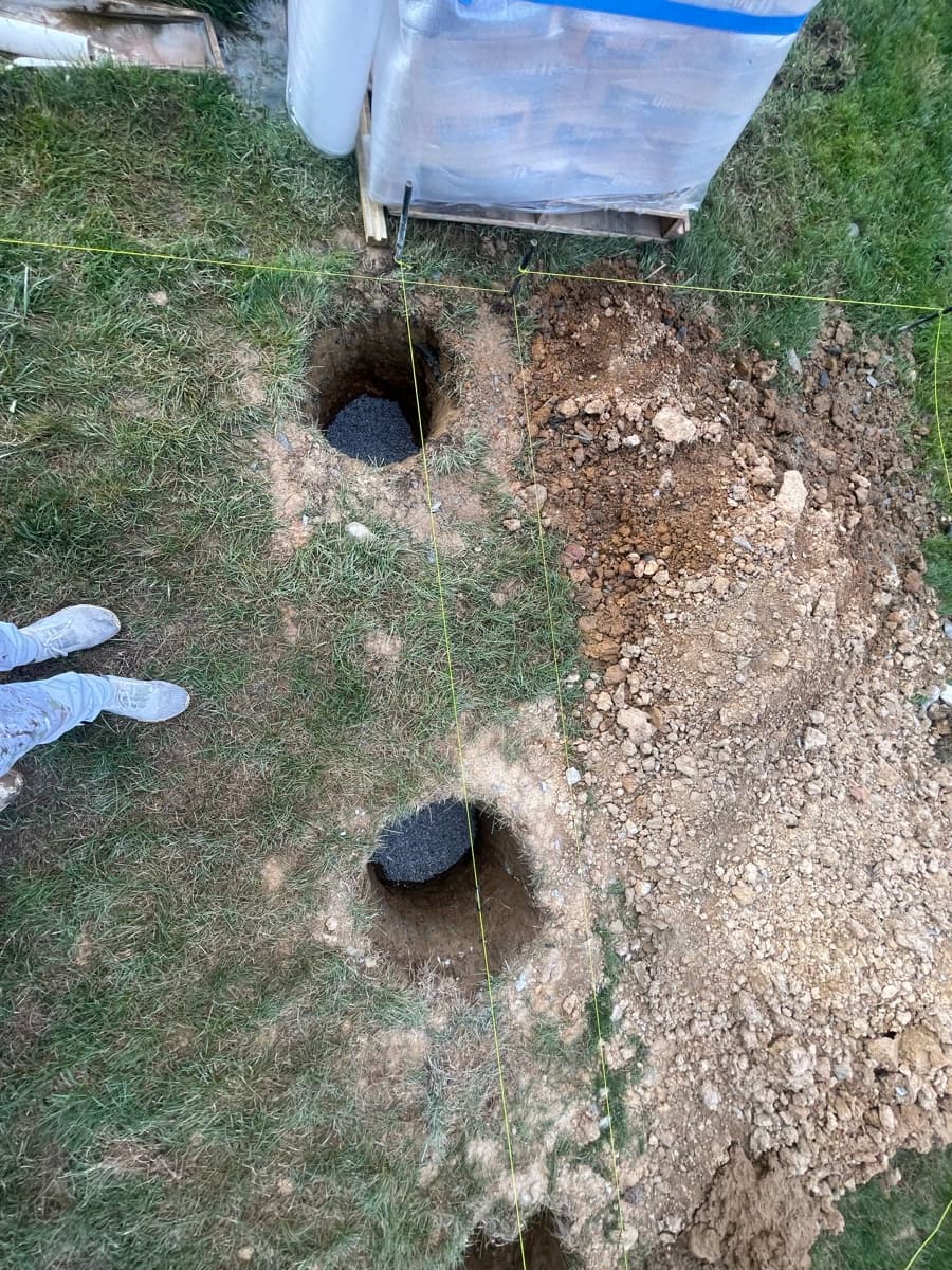 Deck footing holes dug in a backyard
