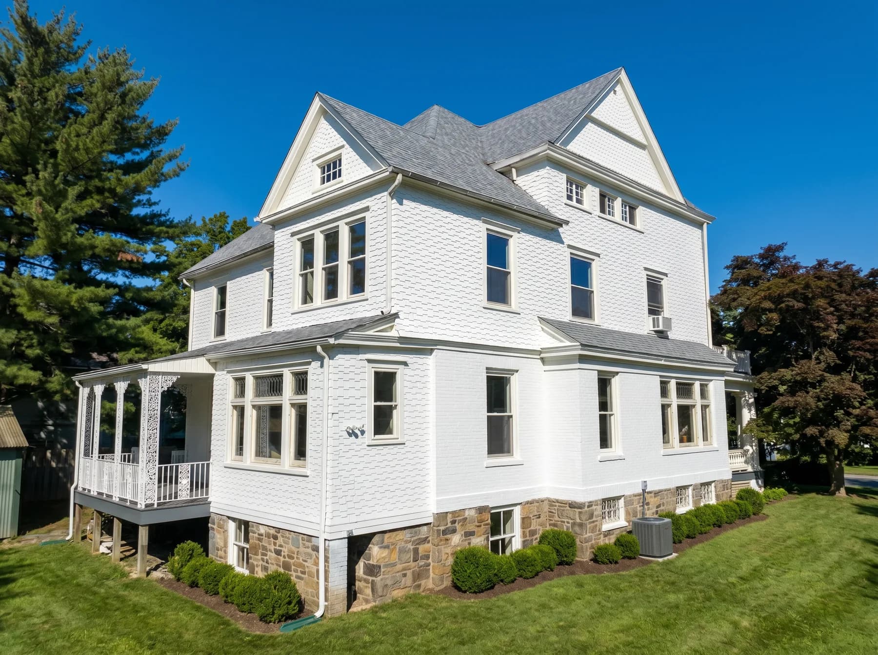 Side view of finished white exterior house painting in Bethlehem PA with stone foundation