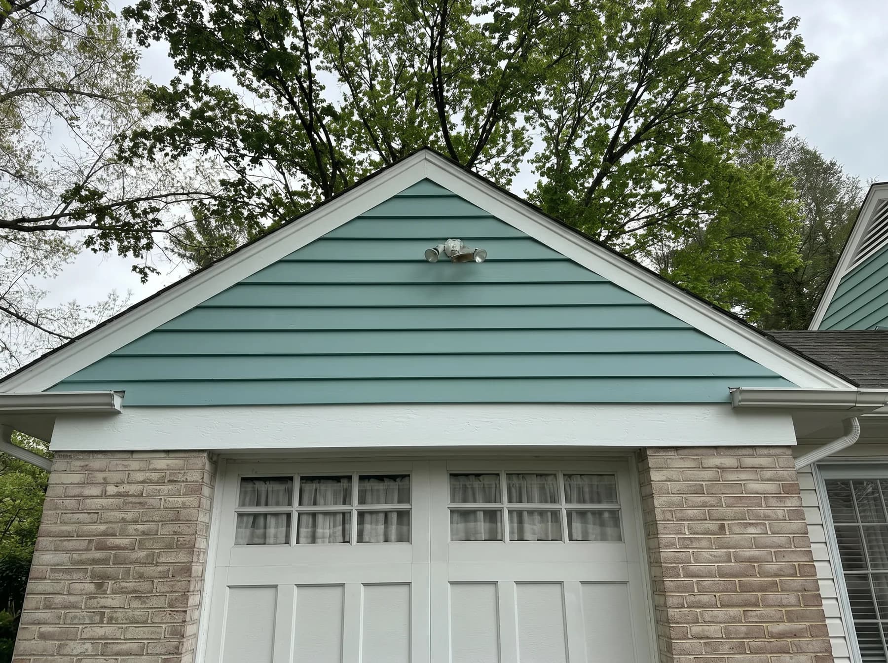 Finished garage gable with white trim and blue green siding in South Whitehall Township