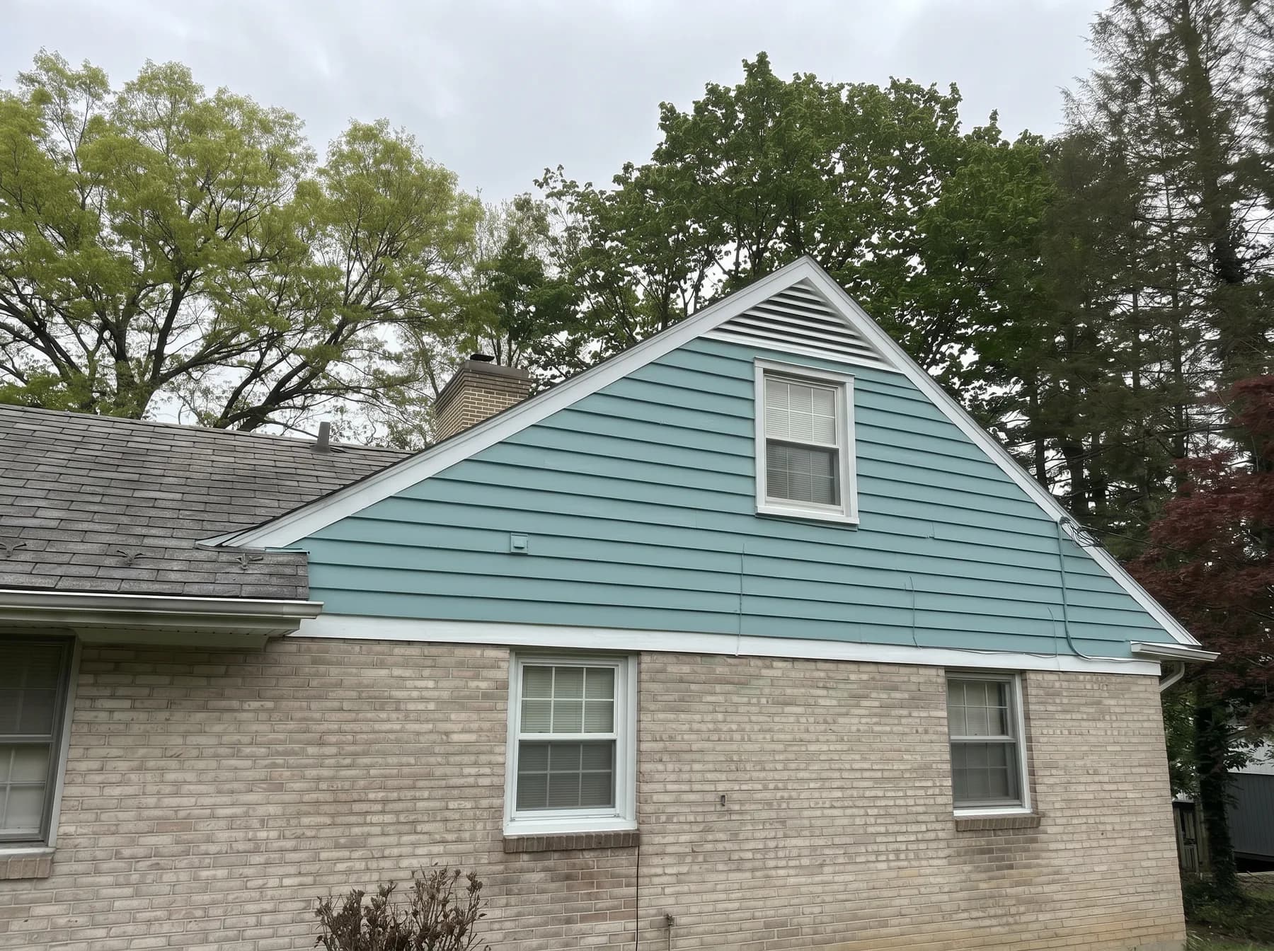 Finished side elevation with painted blue green siding and brick exterior near Allentown PA