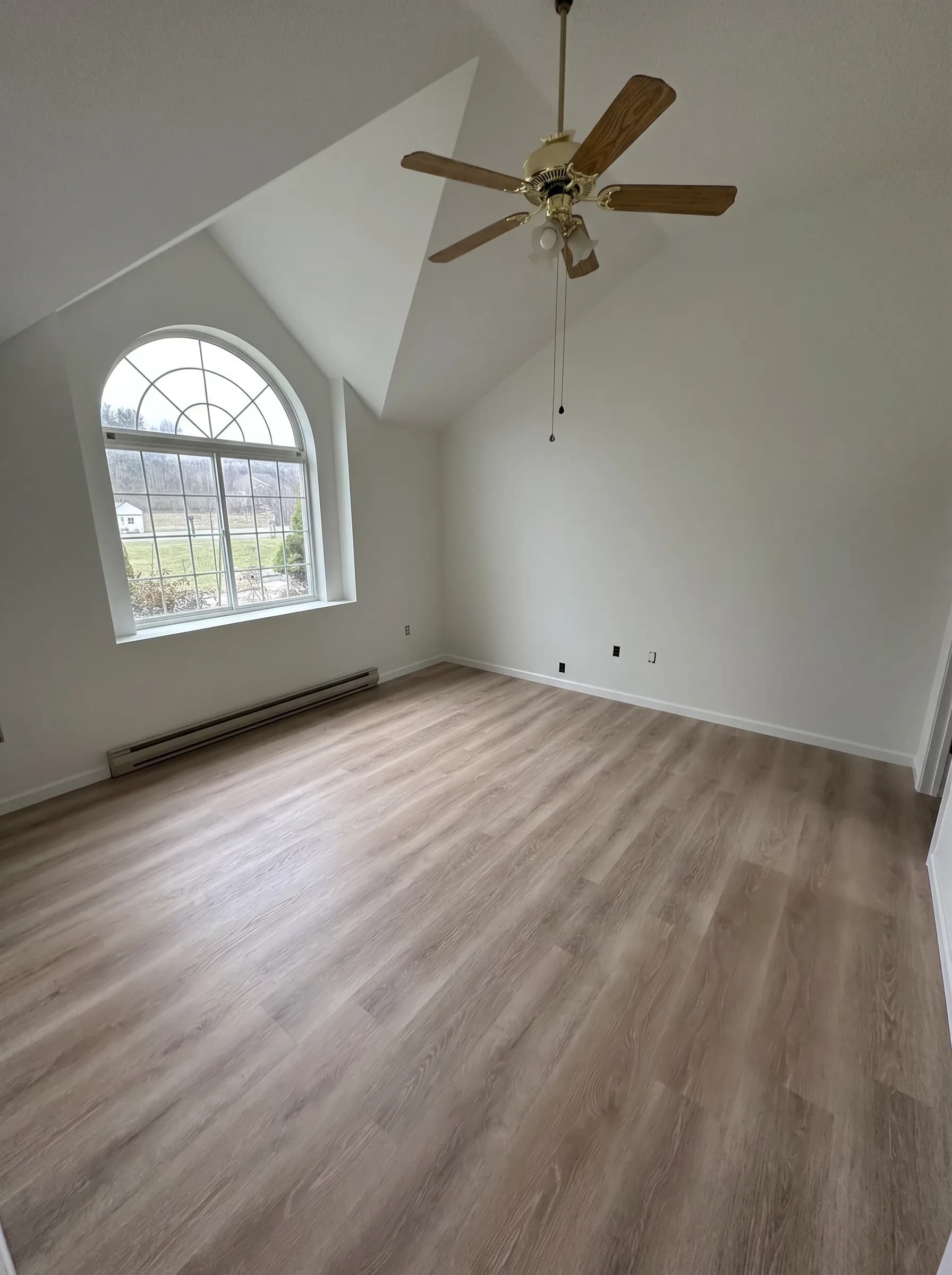 Finished vaulted room with arched window and wood-look flooring in Southside Allentown