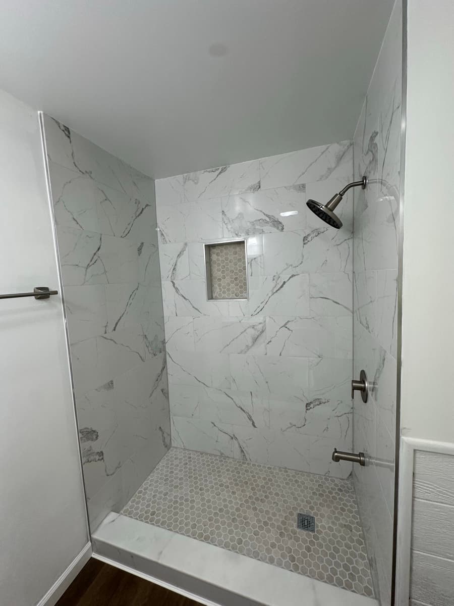 Completed shower walls and floor with marble-look tile