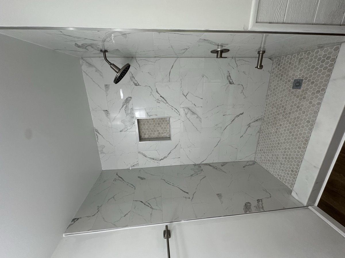 Completed shower walls and floor with marble-look tile
