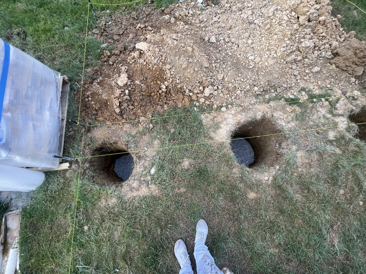 Deck footing holes dug in a backyard