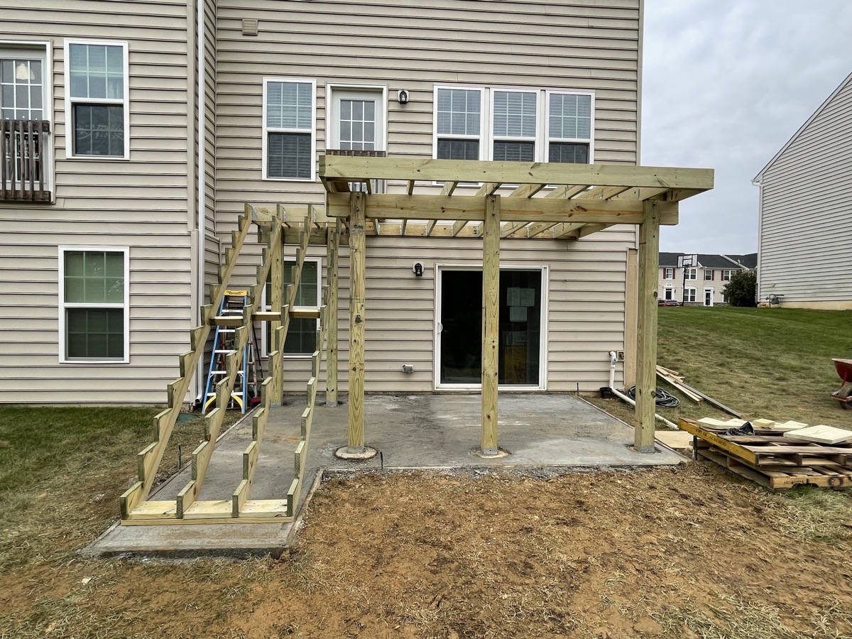 Rear deck framing under construction behind a house