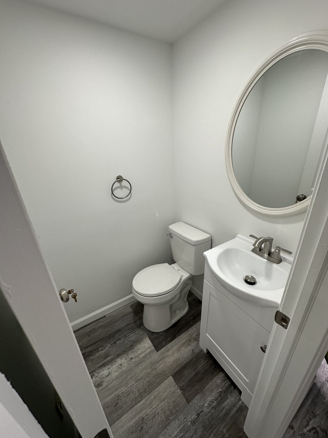 Finished small bathroom with vanity and round mirror in Bethlehem